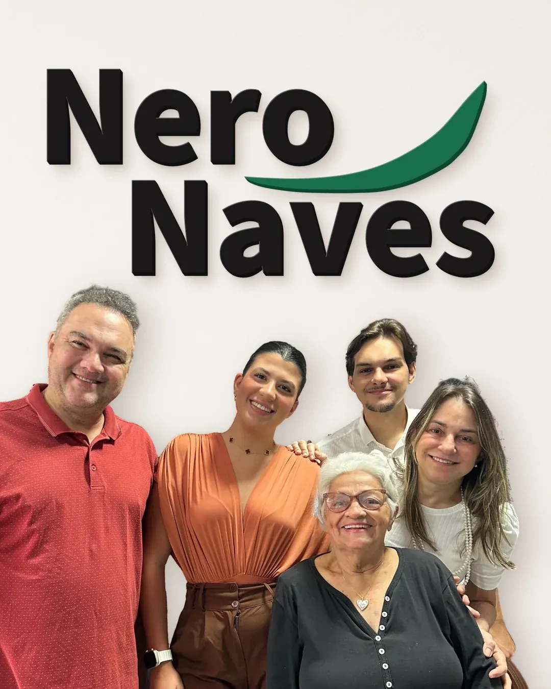 O logo da NeroNaves em letras grandes na parede e, na frente, a família de dentistas abraçada a uma paciente, uma senhora de cabelo branco.